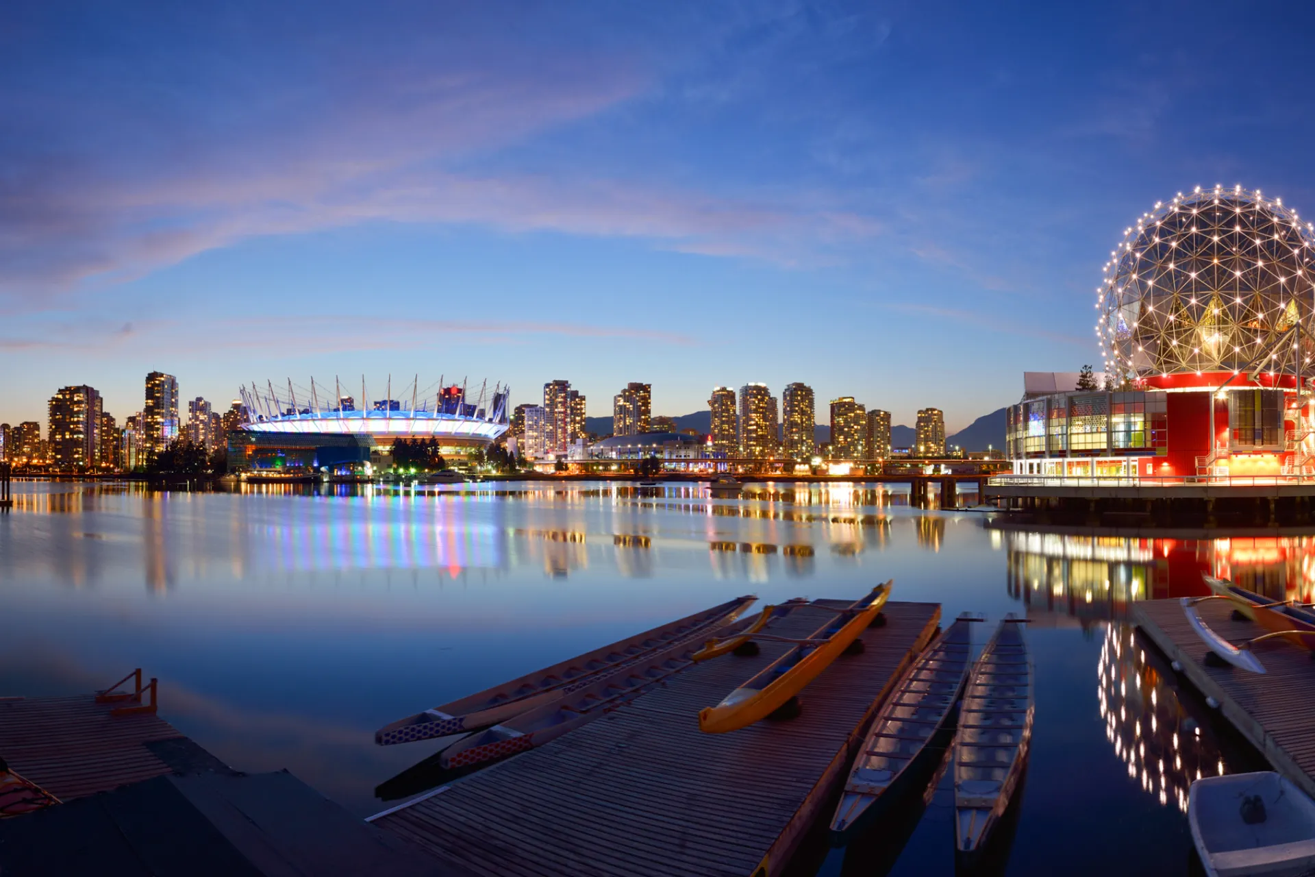 Kvällsljus över False Creek i Vancouver med skyline, BC Place och det upplysta Science World speglat i det stilla vattnet
