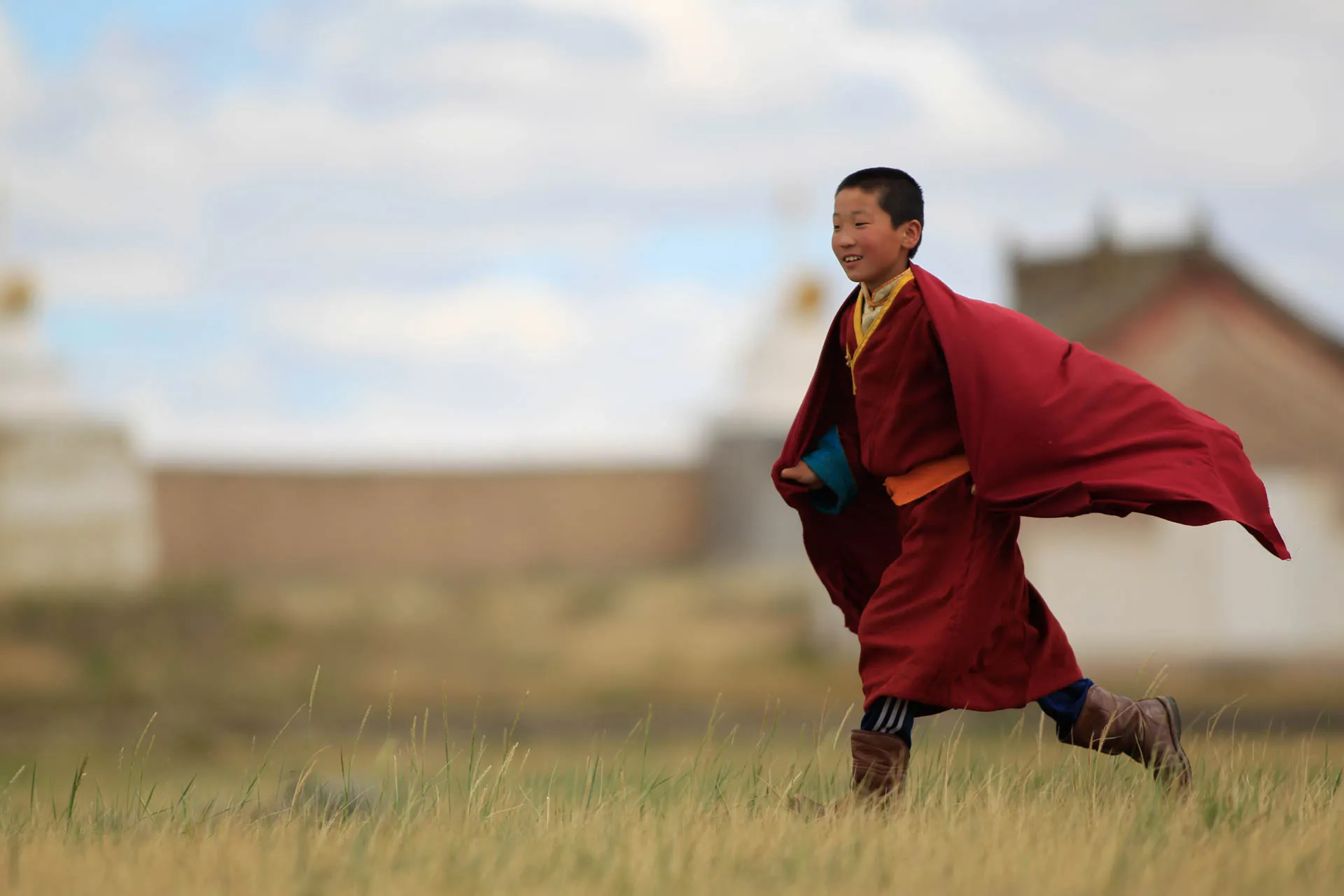 Ung buddhistmunk i Mongoliet iförd traditionell röd munkkåpa