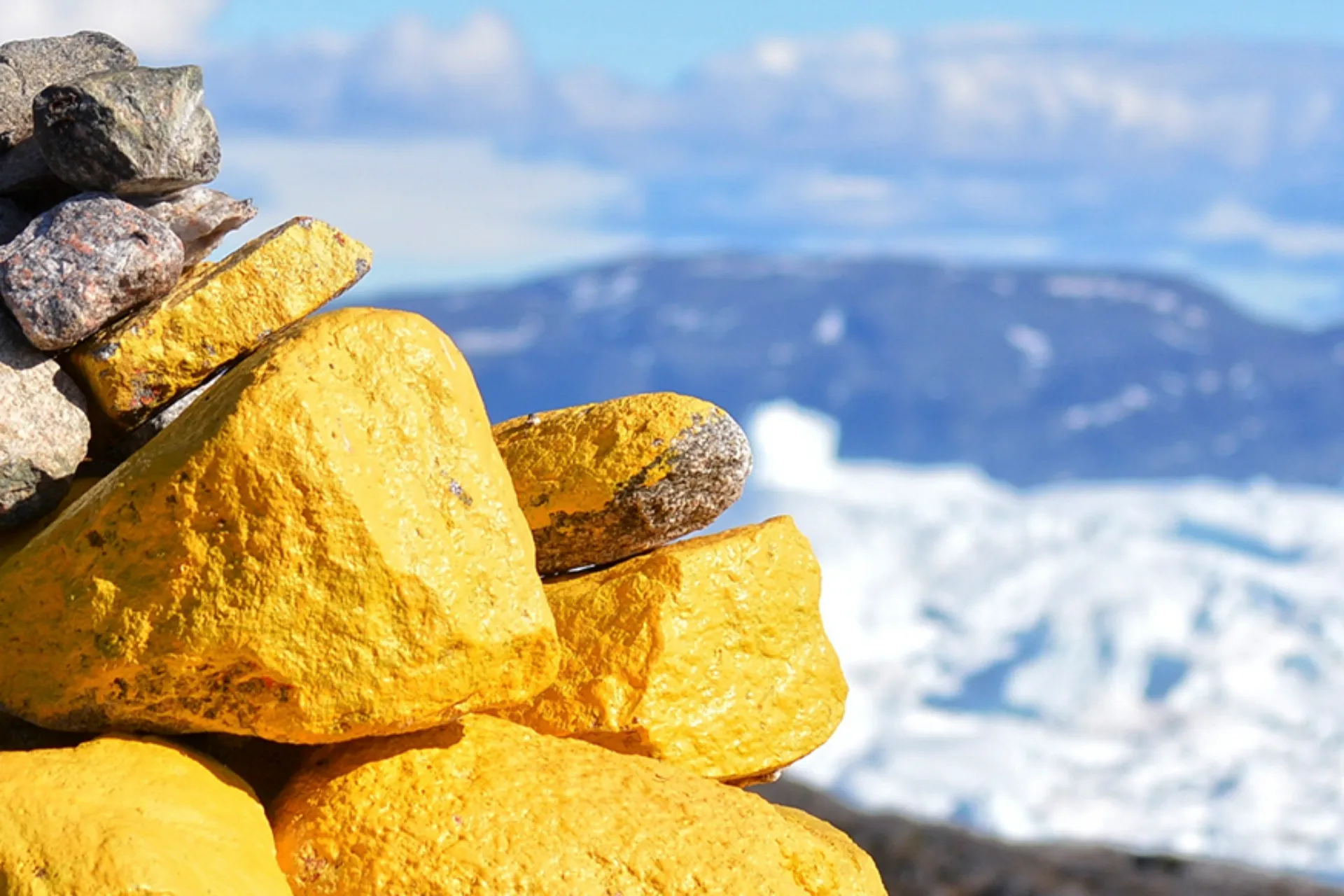 En vardestack med gula och grå stenar med utsikt över isfjorden En vardestack med gula och grå stenar med utsikt över isfjorden