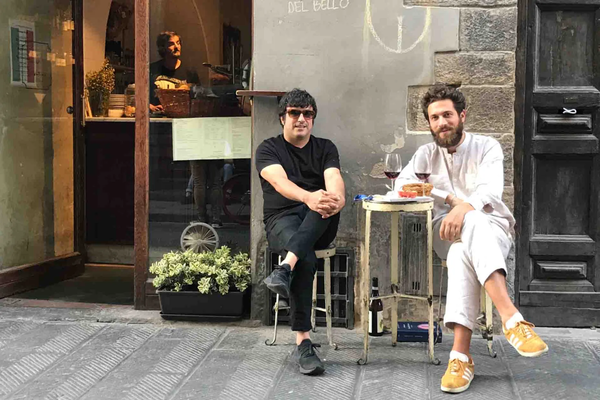Två män njuter av ett glas vin vid ett litet bord på gatan Två män njuter av ett glas vin vid ett litet bord på gatan