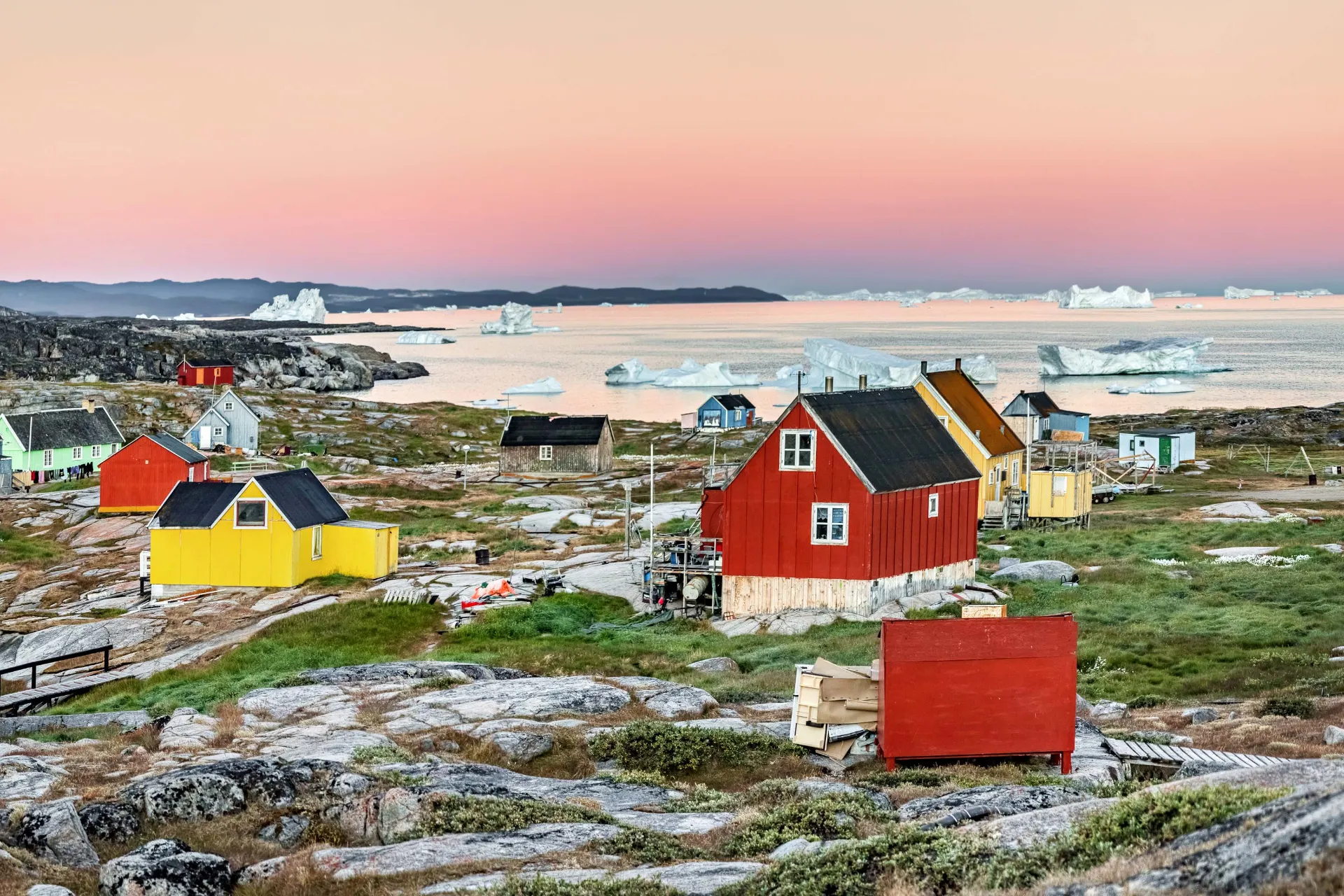 Oqaatsut i Västra Grönland badat i mjukt morgonljus med isberg vid horisonten Oqaatsut i Västra Grönland badat i mjukt morgonljus med isberg vid horisonten