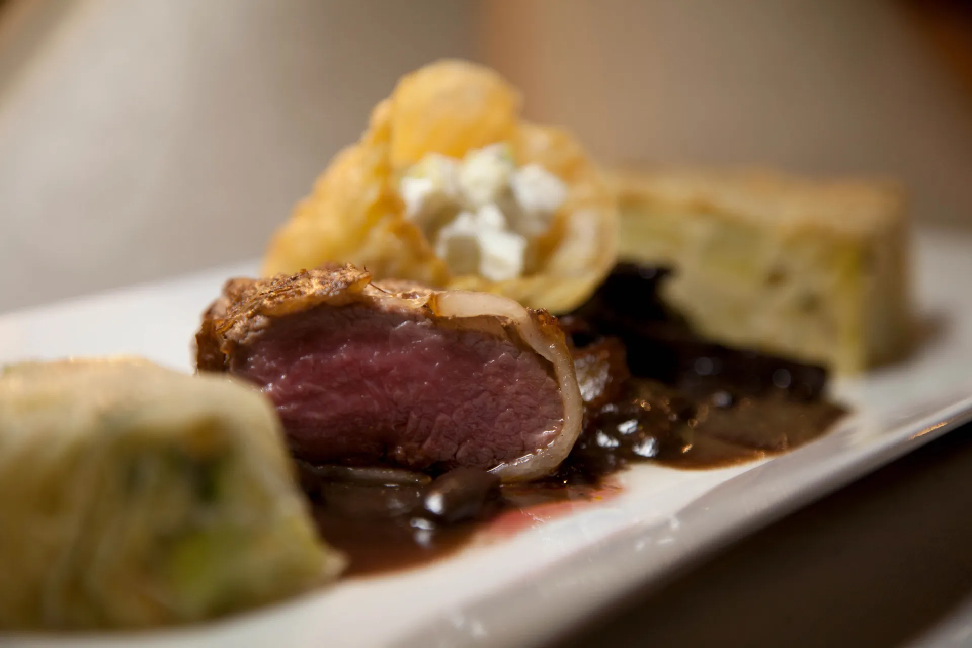 Upplagd tallrik med rosastekt renkött, sås och tillbehör Upplagd tallrik med rosastekt renkött, sås och tillbehör