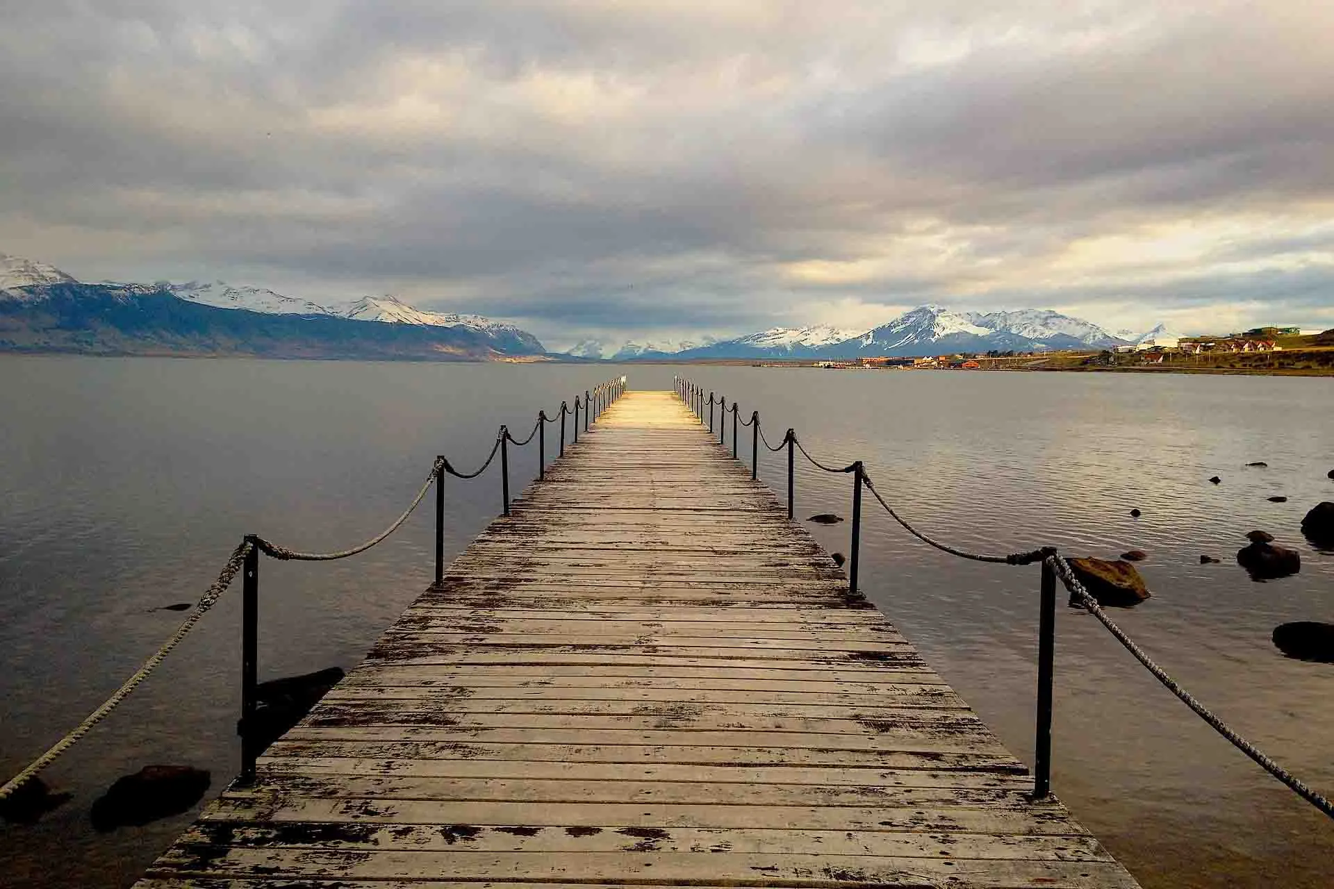 Från träbron vid Puerto Natales har man utsikt över Última Esperanza-fjorden och de omgivande bergen