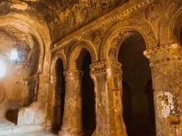 Inre av en gammal grottkyrka i Kappadokien, med uthuggna pelare, bågar och rester av dekorationer i klippväggarna Inre av en gammal grottkyrka i Kappadokien, med uthuggna pelare, bågar och rester av dekorationer i klippväggarna