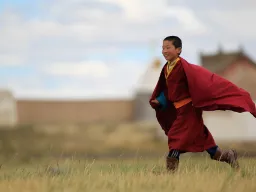 Ung buddhistmunk i Mongoliet iförd traditionell röd munkkåpa