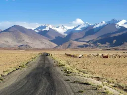 En öde och karg sträcka längs den berömda Pamir Highway med Tadzjikistans snötäckta bergstoppar i bakgrunden