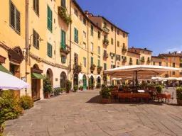 Torget Piazza dell’Anfiteatro med kaféer och gula hus Torget Piazza dell’Anfiteatro med kaféer och gula hus