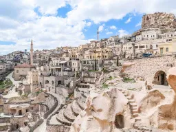 Uchisar-slottet i Kappadokien reser sig över staden, omgiven av hus och grottor uthuggna i de mjuka klipporna Uchisar-slottet i Kappadokien reser sig över staden, omgiven av hus och grottor uthuggna i de mjuka klipporna