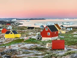 Oqaatsut i Västra Grönland badat i mjukt morgonljus med isberg vid horisonten Oqaatsut i Västra Grönland badat i mjukt morgonljus med isberg vid horisonten