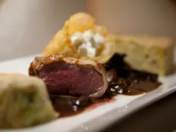 Upplagd tallrik med rosastekt renkött, sås och tillbehör Upplagd tallrik med rosastekt renkött, sås och tillbehör