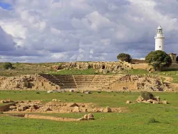 Odeon-teatern i Paphos arkeologiska park med den karakteristiska fyren i bakgrunden