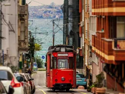 Den ikoniska röda spårvagnen slingrar sig genom stadens gator med Bosporen i bakgrunden