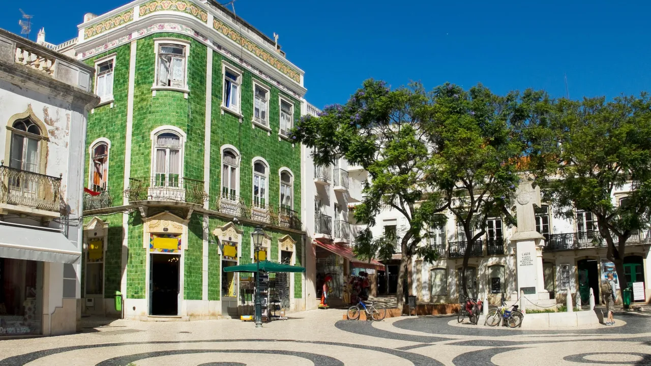 Charmigt torg i Lagos med grönt kakelhus och klassiskt portugisiskt gatstensmönster Charmigt torg i Lagos med grönt kakelhus och klassiskt portugisiskt gatstensmönster