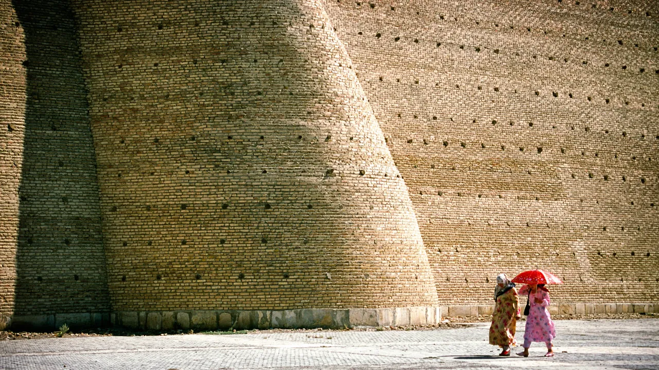 Buchara, Uzbekistan – den historiska stadsmuren med människor i förgrunden