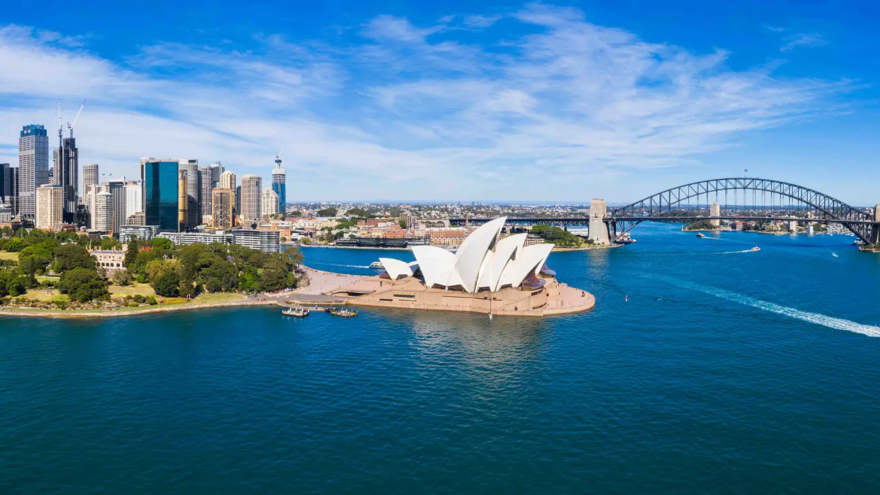 Flygbild över Sydney med hamnbron, Operan och stadens skyline