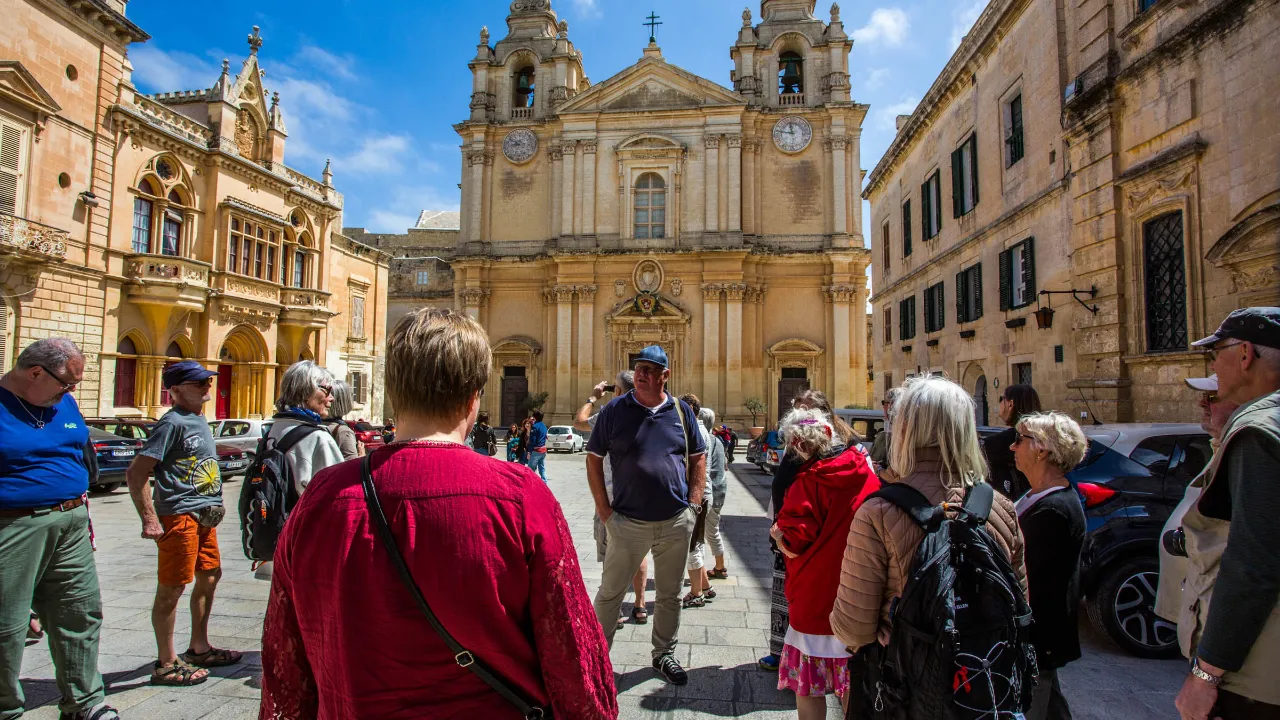 Guiden på jobbet i Mdina, Maltas gamla huvudstad, framför den imponerande S:t Pauls katedral Guiden på jobbet i Mdina, Maltas gamla huvudstad, framför den imponerande S:t Pauls katedral