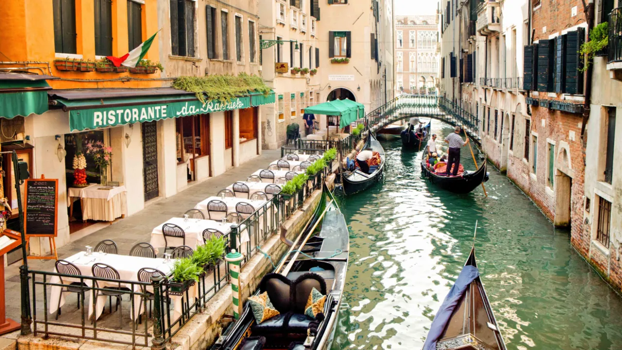 Gondoler på en kanal i Venedig med restauranger och historiska byggnader