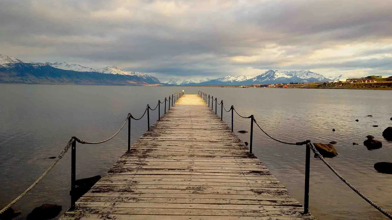 Från träbron vid Puerto Natales har man utsikt över Última Esperanza-fjorden och de omgivande bergen