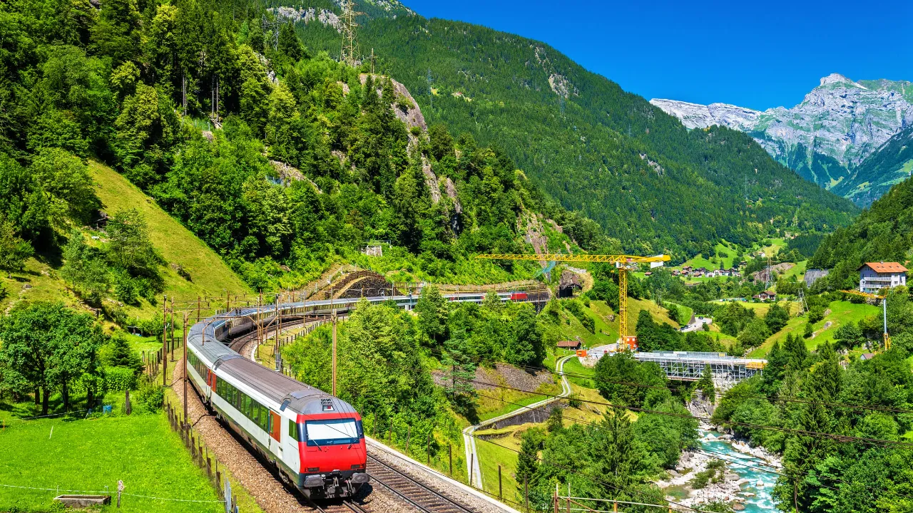 Tåg på Gotthardbanan genom den frodiga alpina dalen Tåg på Gotthardbanan genom den frodiga alpina dalen